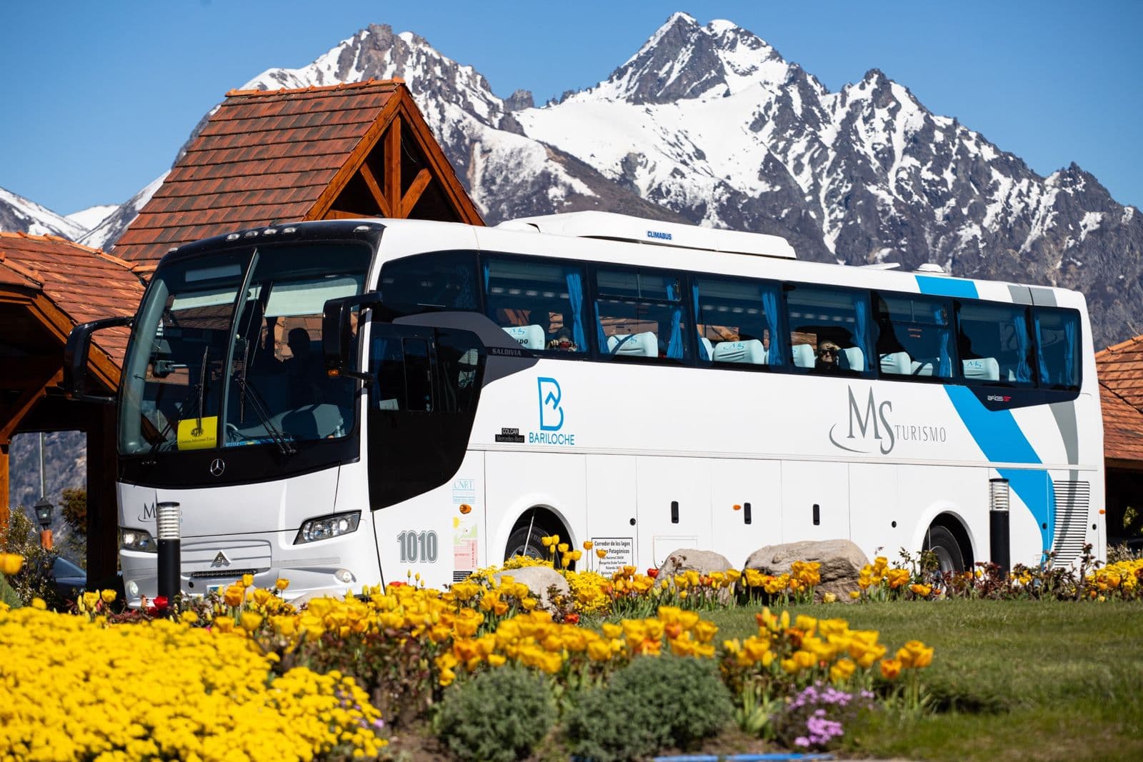 Micro de MS Turismo con los cerros nevados de Bariloche de fondo