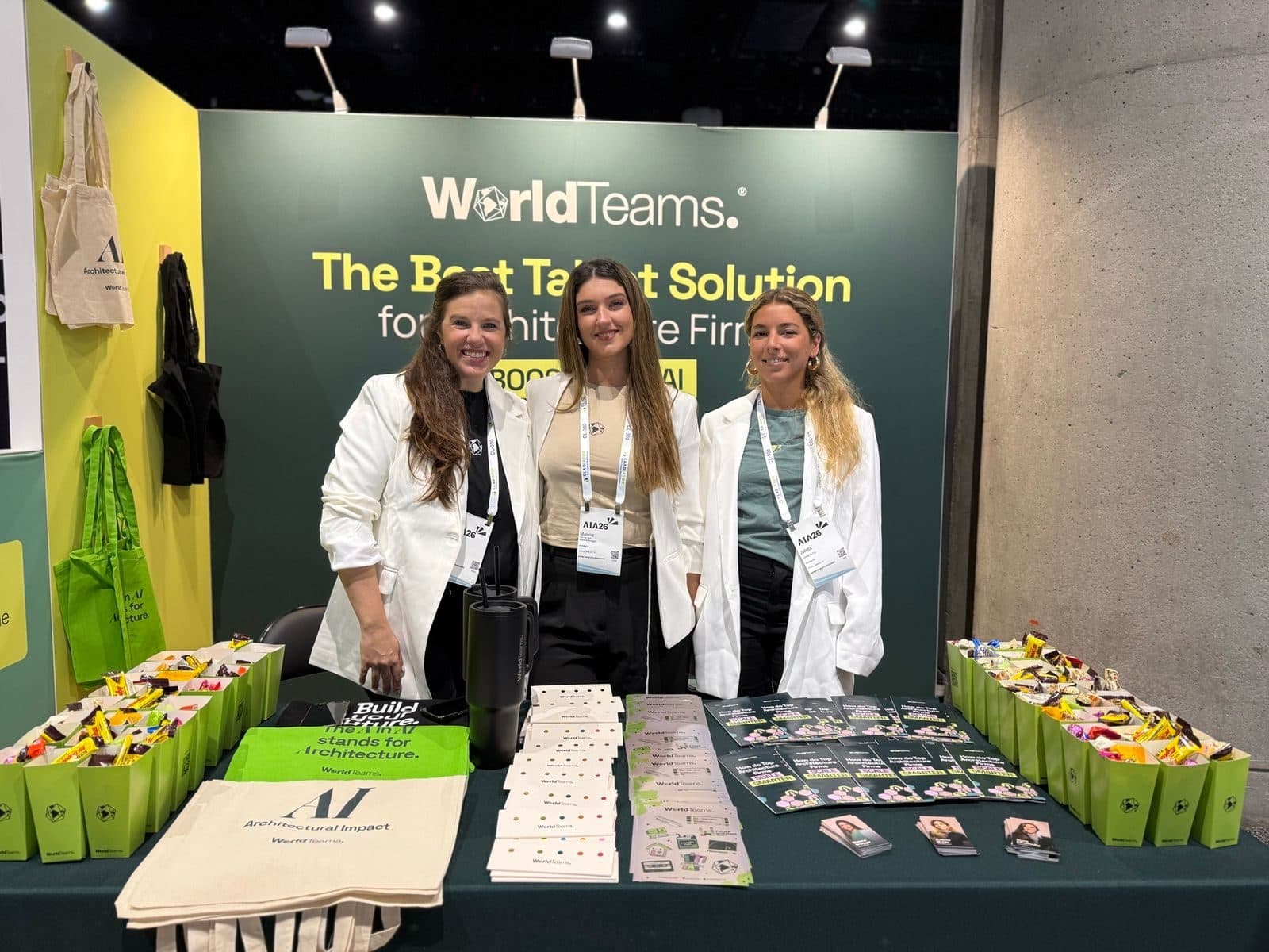 Stand de WorldTeams en una feria, con el cartel de su servicio para estudios de arquitectura