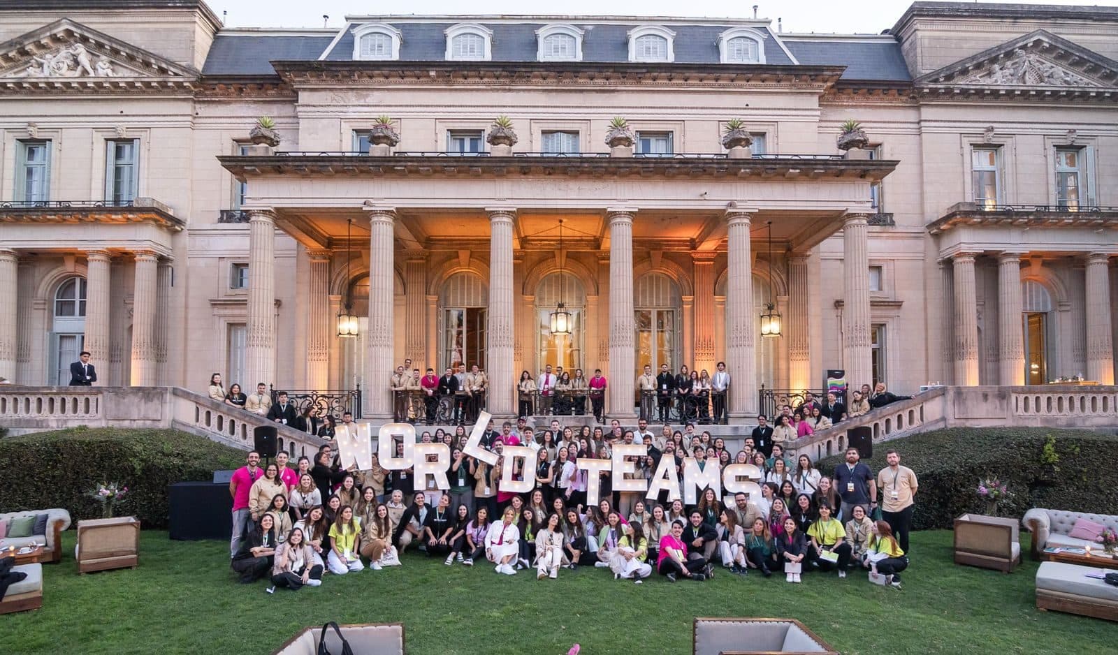 El equipo de WorldTeams frente a una casona, con las letras de la marca en el jardín